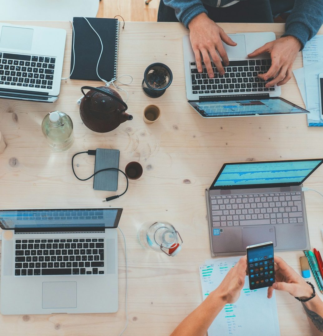 Freie Wähler Röttenbach e.V. - Für KMU Mehrere Personen arbeiten an Laptops und verwenden Mobilgeräte auf einem Tisch.